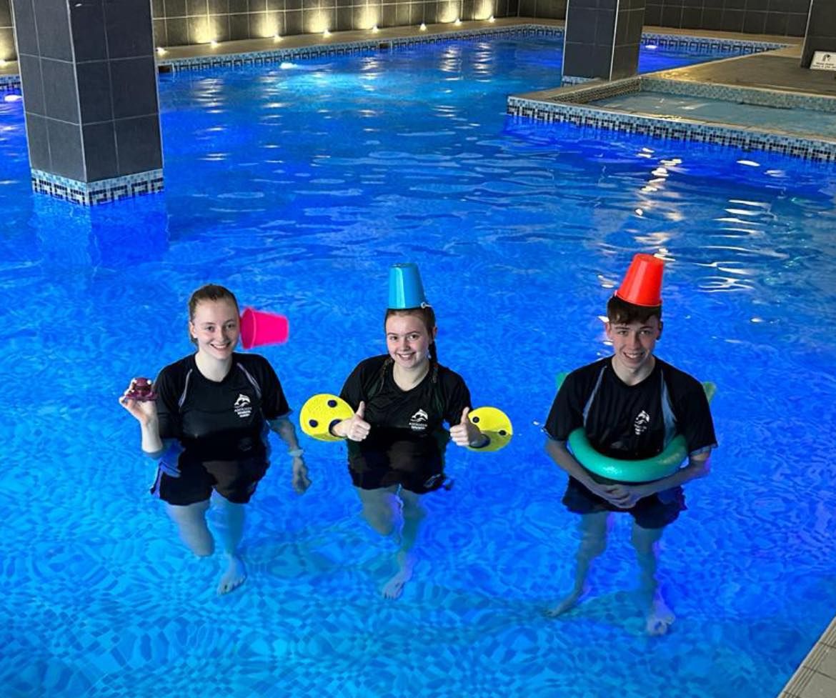 Three Academy team members with colourful floats and cones in the pool