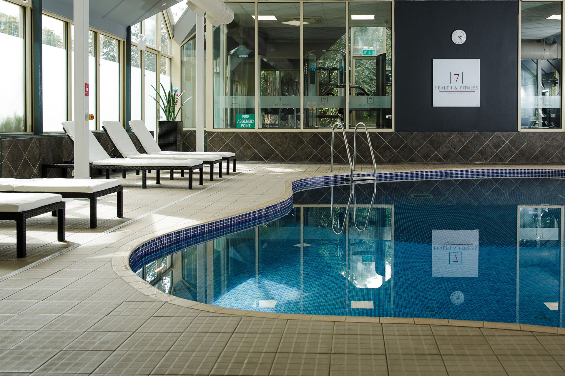 The indoor pool at Landmark Health & Fitness, with poolside loungers and large windows