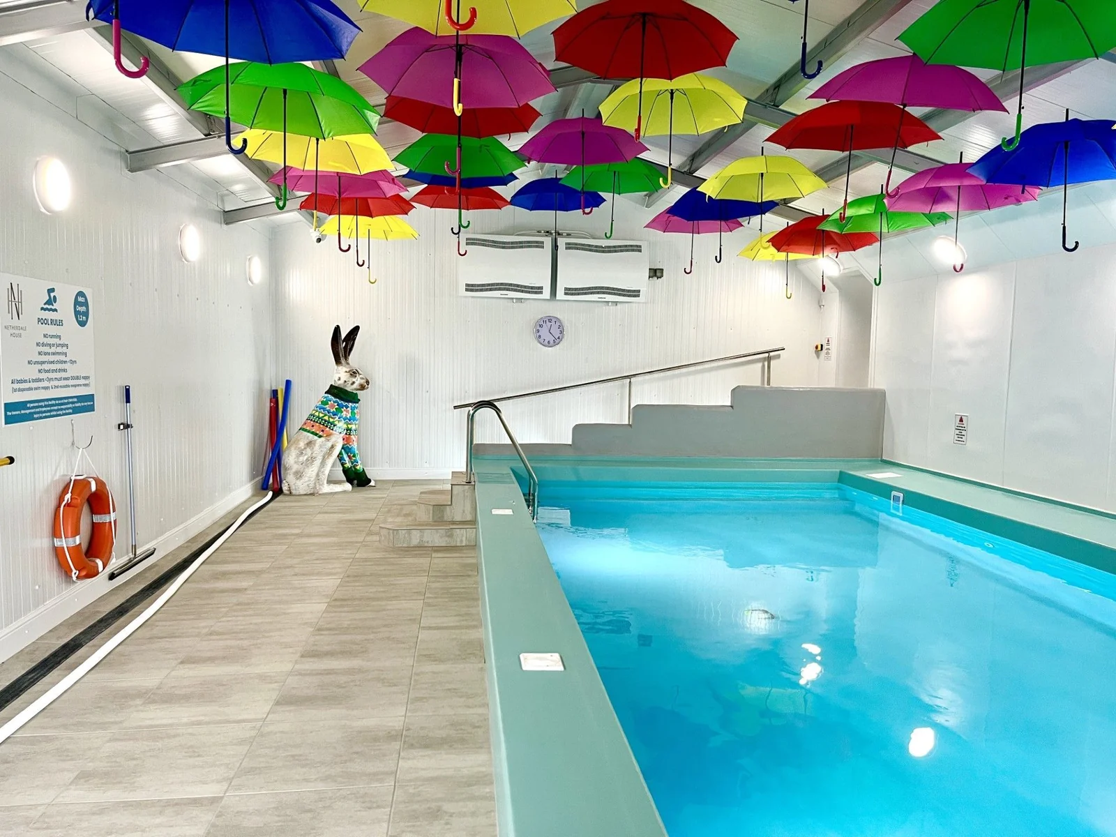 The indoor swimming pool at Netherdale House, with colourful umbrellas overhead